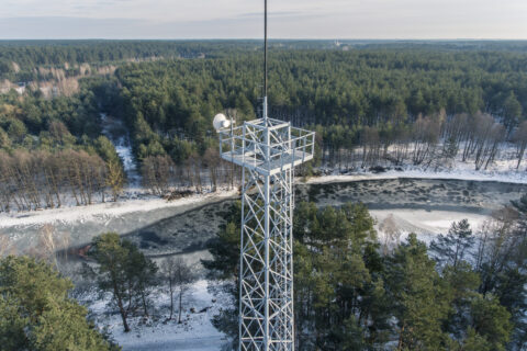 Aerial view of a fire tower near frozen lake during winter season.